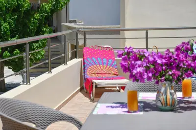 a table with a vase of purple flowers on a balcony at Katerina's house in Kefálion