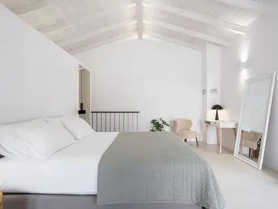 a white bedroom with a large bed and a desk at Lithos Retreat (ΛΙTHOS Retreat) in Kolymvari