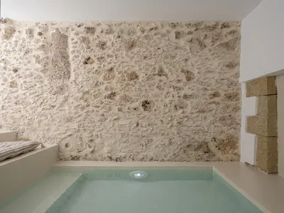 a bath tub in a room with a stone wall at Lithos Retreat (ΛΙTHOS Retreat) in Kolymvari