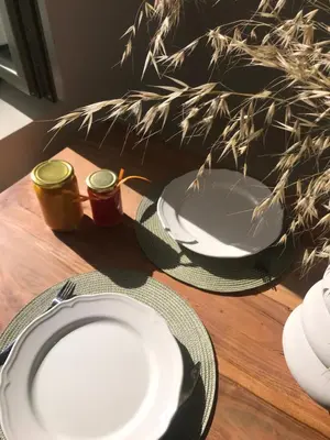 a table with white plates on a wooden table at Lithos Retreat (ΛΙTHOS Retreat) in Kolymvari