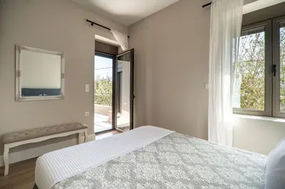 a white bedroom with a bed and a window at Amalthia Casa by 8essentially in Chania Town