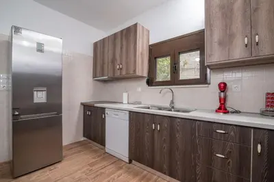 a kitchen with wooden cabinets and a stainless steel refrigerator at Vintage project house in Kalyves