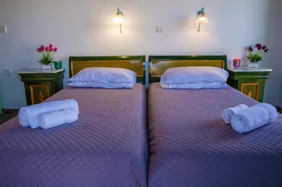 two beds in a room with purple sheets and pillows at Villa Jokasta & Erato in Chania Town