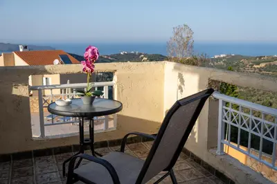 a table and two chairs on a balcony with a flower at Villa Jokasta & Erato in Chania Town