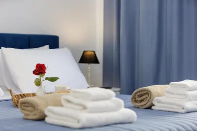 a pile of towels and a rose on a bed at Adelphes Beachfront Apartment with direct connection to the beach in Chania Town