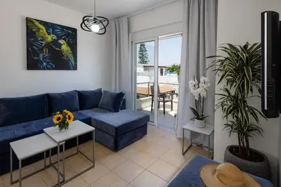 a living room with a blue couch and a table at Adelphes Beachfront Apartment with direct connection to the beach in Chania Town