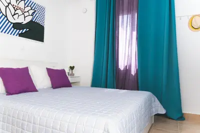a bedroom with a bed with blue and purple curtains at Origeo casa in Maleme