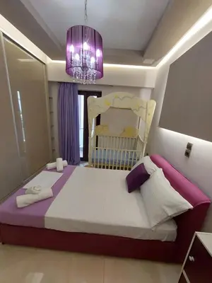 a bedroom with a large bed and a purple chandelier at Rika’s seaside apartments in Chania Town
