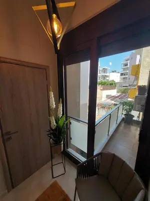 a room with a balcony with a door and a chair at Rika’s seaside apartments in Chania Town