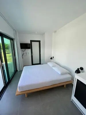 a white bedroom with a bed and a tv at Lefko Apartments in Tavronitis