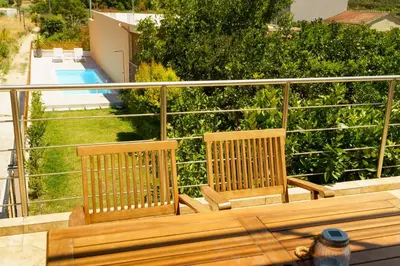 a wooden bench sitting on top of a balcony at Arch Houses - Nature Escape with Shared Pool in Spiliá