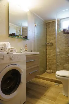 a bathroom with a washing machine and a shower at Arch Houses - Nature Escape with Shared Pool in Spiliá