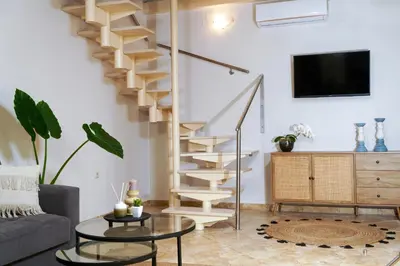 a spiral staircase in a living room with a couch and a table at Arch Houses - Nature Escape with Shared Pool in Spiliá