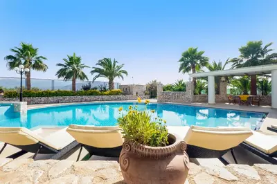 a swimming pool with chairs and a vase with a plant at Epavlis Akrotiri in Chania Town