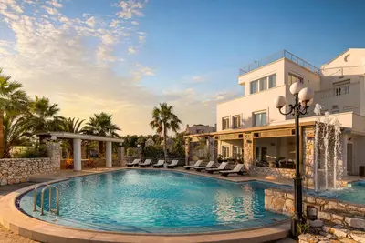 a pool in front of a building with palm trees at Epavlis Akrotiri in Chania Town