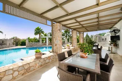 a patio with a table and chairs next to a swimming pool at Epavlis Akrotiri in Chania Town