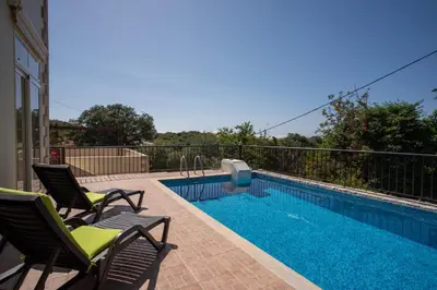 a swimming pool with two chairs next to a house at Villa Festos in Voúvai