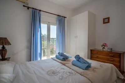 a bedroom with a bed with blue towels on it at Villa Festos in Voúvai