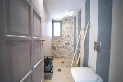 a bathroom with a toilet and a ladder next to a door at Aiolos Executive Suite in Galatás