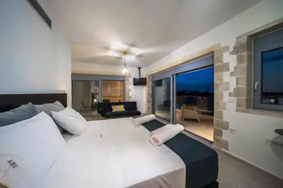 a bedroom with a large white bed and a living room at Aiolos Executive Suite in Galatás