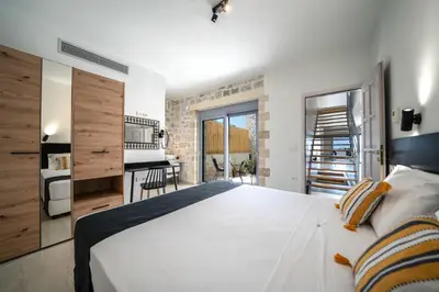 a bedroom with a large white bed and a kitchen at Aiolos Executive Suite in Galatás