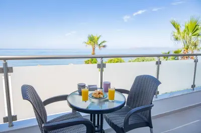 a table and chairs on a balcony with a view of the ocean at Queen Mary Beachfront Studios in Agia Marina Nea Kydonias
