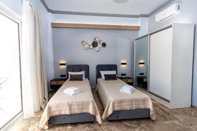 two beds in a room with blue walls at Queen Mary Beachfront Studios in Agia Marina Nea Kydonias