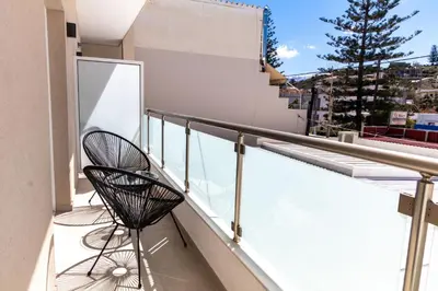 two chairs sitting on the balcony of a building at Queen Mary Beachfront Studios in Agia Marina Nea Kydonias