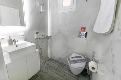 a white bathroom with a toilet and a sink at Queen Mary Beachfront Studios in Agia Marina Nea Kydonias