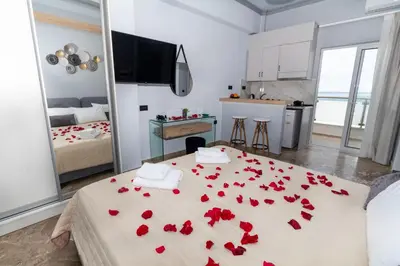 a room with a bed with red roses on it at Queen Mary Beachfront Studios in Agia Marina Nea Kydonias