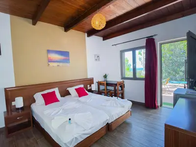 a bedroom with a bed with white sheets and red pillows at Beautiful Life Rooms with Sea View - Next to Elafonisi Beach in Elafonisi