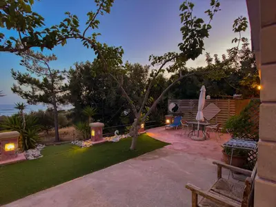 a patio with a table and a chair in a yard at Beautiful Life Rooms with Sea View - Next to Elafonisi Beach in Elafonisi