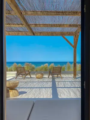two benches sitting on a patio with the ocean in the background at Kaliva Residence in Kalyves