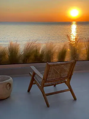 a wicker chair sitting on a balcony watching the sunset at Kaliva Residence in Kalyves