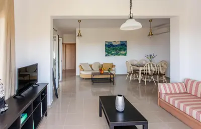 a living room with a couch and a tv at Hillside Seaview Apartment in Stalos