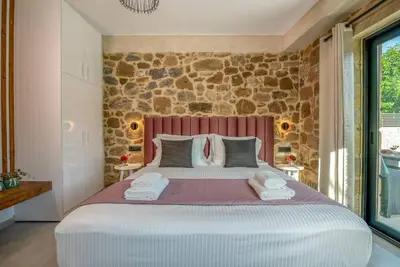 a bedroom with a large bed and a stone wall at White House Boutique in Koukounará