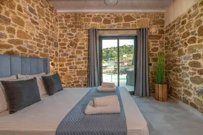 a bedroom with a large bed with a stone wall at White House Boutique in Koukounará