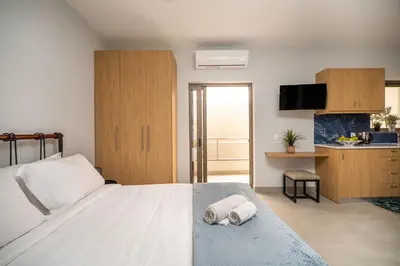 a bedroom with a large white bed and a kitchen at Cozy Spot near the beach in Plataniás