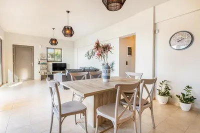 a dining room and living room with a wooden table and chairs at Celeste Suite on the Beach in Agia Marina Nea Kydonias