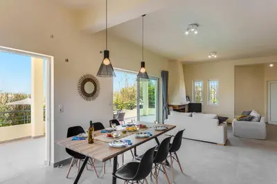 a dining room with a wooden table and chairs at Villa Aggeliki by Villa Plus in Pírgos Psilonérou