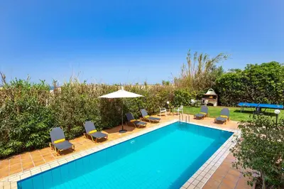 a swimming pool with chairs and an umbrella at Villa Aggeliki by Villa Plus in Pírgos Psilonérou