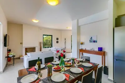 a dining room with a table and a living room at Villa Ilos by Villa Plus in Pírgos Psilonérou