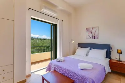 a bedroom with a bed and a large window at Villa Ilos by Villa Plus in Pírgos Psilonérou