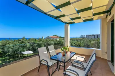 a patio with a glass table and chairs on a balcony at Villa Ilos by Villa Plus in Pírgos Psilonérou
