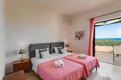 two beds in a bedroom with a view of the ocean at Villa Ilos by Villa Plus in Pírgos Psilonérou