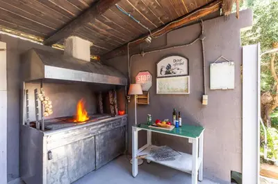 an outdoor kitchen with a pizza oven with a table at Villa Liostasi by Villa Plus in Agia Marina Nea Kydonias