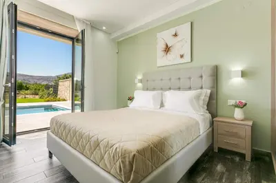 a bedroom with a bed and a sliding glass door at Villa Potami Angela by Villa Plus in Stílos