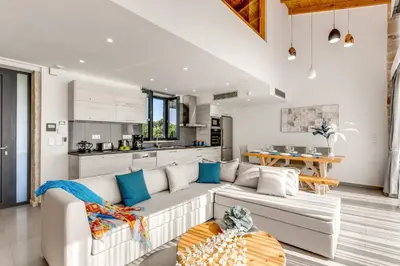 a living room with a white couch and a kitchen at Villa Potami Angela by Villa Plus in Stílos