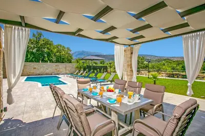a patio with a table and chairs and a pool at Villa Potami Nikos by Villa Plus in Stílos