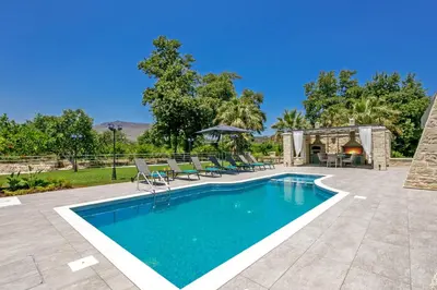 a swimming pool in a yard with chairs and a table at Villa Potami Nikos by Villa Plus in Stílos